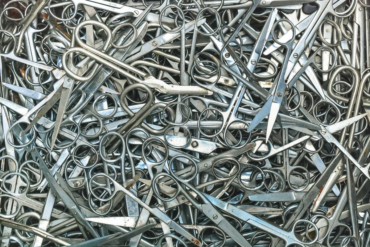 Infographic comparing stainless steel vs carbon steel vs plastic-coated scissors showing rust resistance, edge retention, and hygiene ratings